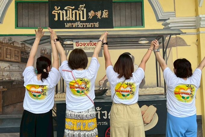 タイの街で腕を上げてポーズをとるメンバー